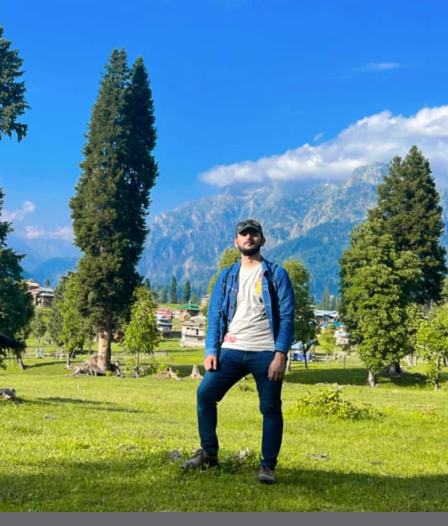 Standing in a valley in front of pine trees and mountains